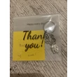 A kulcstartó és a cetli áttetsző, &quot;Thank you! Happy days&quot; feliratú műanyag tasakban.