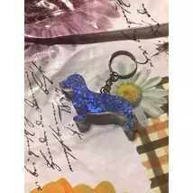 Ezüst kulcskarikán ezüst lánc lóg, kék flitteres tacskó alakú kutya látható. 
