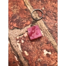 Ezüst kulcskarikán ezüst lánc lóg, cegy rózsaszín ajándék doboz tapintható ki.