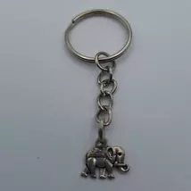 Ezüstszínű kulcskarikáról lánc lóg le, rajta ezüstszínű elefánt medál. Az elefánt hátán nyeregszerű ponyva. 