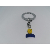Ezüstszínű kulcskarikáról lánc lóg le, rajta a kulcstartó: legóember mellkastól felfelé, sárga színben, kék ruhában.