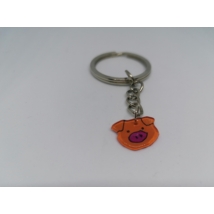 Ezüstszínű kulcskarikáról lánc lóg le, rajta a kulcstartó: narancssárga malacfej rózsaszín orral.