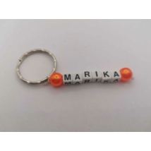 Ezüstszínű kulcskarikáról lelógó Marika szó betűgyöngyökből, két oldalán egy-egy gömbalakú, narancssárga gyönggyel. A betűgyöngyök kockaalakúak, fehér alapon feketék, elforgatva is ugyanazt mutatják.
