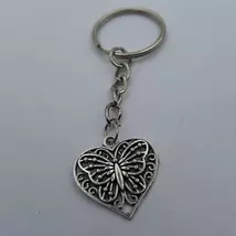 Ezüstszínű kulcskarikáról lánc lóg le, rajta nagyobb fajta medál: egy szív, amin pillangó terül el. 
