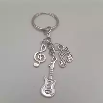 Ezüstszínű kulcskarikáról láncon lóg le három különböző szinten három külöböző medál: gitár, violinkulcs és ti-ti hangjegy.