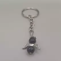 Ezüstszínű kulcskarikáról lelógó angyal kulcstartó: két gömbalakú ásványgyöngy között ezüstszínű, szívmintás szárny, tetején ezüst glória. Az ásványgyöngyök fekete alapon bőrmintás ónixok.