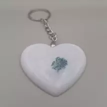 Ezüstszínű kulcskarikáról láncon lóg le egy fehér gyanta szív, benne apró, kék, préselt virággal.