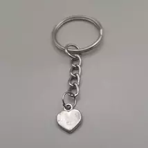 Ezüstszínű kulcskarkikáról láncon lelógó ezüstszínű medál: apró, egyszerű szív.
