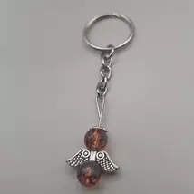 Ezüstszínű kulcskarikáról lelógó angyal kulcstartó: két gömbalakú gyöngy között ezüstszínű, szívmintás szárny, tetején ezüst glória. Az gyöngyök pirosas-lilásak, áttetszőek.