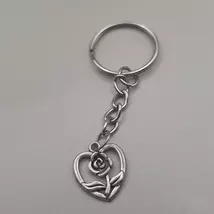 Ezüstszínű kulcskarkikáról láncon lelógó ezüstszínű medál: nyitott szív, közepén rózsával.