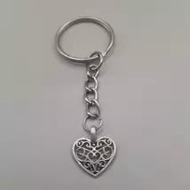 Ezüstszínű kulcskarkikáról láncon lelógó ezüstszínű medál: szív kacskaringós mintával.