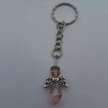 Ezüst kulcskarikára és rövid láncra fűzött, angyal alakú kulcstartó. Az angyalnak pici ezüst glóriája, gömbalakú, fazettázott, rózsaszín feje, ezüstszínű szárnya és cseppalakú, fazettázott, rózsaszín szoknyája van. 