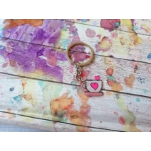 Ezüstszínű kulcskarikáról lelógó láncon kulcstartó: fehér csésze rózsaszín füllel és tálcán, szív mintával és szívben végződő kanállal.