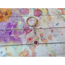 Ezüstszínű kulcskarikáról lelógó láncon kulcstartó: fehérbőrű stilizált várandós női alak, pocakján rózsaszín szívvel.