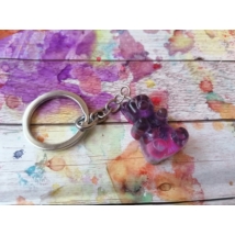 Ezüstszínű kulcskarikáról lelógó láncon kulcstartó: lilás-rósaszínes gumimackó.