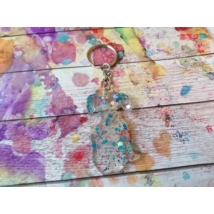 Ezüstszínű kulcskarikáról lelógó láncon kulcstartó: stilizált tacskó alak áttetsző színben, világoskék és rózsaszín flitterekkel tele.