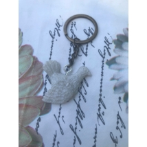 Ezüst kulcskarikán lánc, rajta szemes csavarral rögzített gyantakulcstartó. Fehér színű galambot formáz.