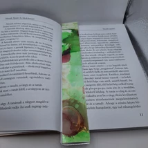 Téglalap alakú könyvjelző világoszöld alappal, rajta vörös gömbökkel.