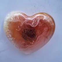 Szív alakú mágnes, amelyen halvány narancs és fehér színek keverednek, a középen található sötétebb tónusokkal. A színek elegáns spirál mintázatot alkotnak.