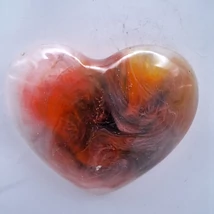 Szív alakú mágnes, amelyet meleg színek uralnak: a vöröses, narancsos és barna árnyalatok keverednek sejtelmes fehéres fátyolokkal. A jobb felső részen sárgás ragyogás jelenik meg, ami egy kis napfényt idéz.