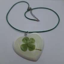 Fekete nyaklánc alapra fűzött műgyanta medál. Sima tapintású szívalakú, fehér alapon igazi négylevelű lóhere van benne.