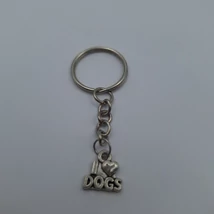 Ezüstszínű kulcskarikáról lánc lóg le, rajta ezüstszínű I love dogs feliratú medál. A love helyén egy szív.