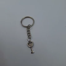 Ezüstszínű kulcskarikáról lánc lóg le, rajta ezüstszínű lapos pezsgős pohár medál. A buborékokat pöttyözött folyadék jelzi.