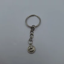 Ezüstszínű kulcskarikáról lánc lóg le, rajta ezüstszínű, köralakú ying-yang medál. A medál nem színezett, különböző felületekkel jelzi a két színt.