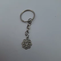 Ezüstszínű kulcskarikáról lánc lóg le, rajta ezüstszínű virág medál, domború szirmokkal.
