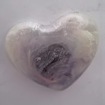 Szívalakú, sima tapintású, tenyérben elférő szív mágnes. Finom, áttetsző fehéres és lilás rétegek örvénylenek benne, mintha fátyolszerű köd borítaná a középen sötétebb, textúrált mintát. A mélyebb részeken enyhe szürke és halvány rózsás árnyalatok sejlene
