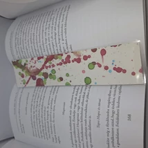 Téglalap alakú könyvjelző: fehér alapon bordó, zöld, barna és kék színű, nonfiguratív, fröccsenésszerű minták díszítik.