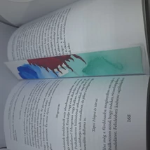 Téglalap alakú könyvjelző: fehér és türkiz alapon kék és bordó színű, nonfiguratív, foltszerű minták díszítik.