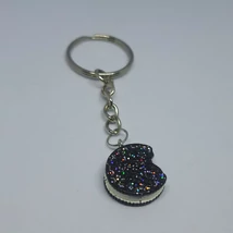 Ezüstszínű kulcskarikáról lánc lóg le, rajta medál: oreora hasonlító barna, fehér krémes keksz, rajta szivárványszínű glitterrel.
