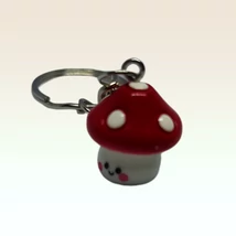 Ezüstszínű kulcskarikáról lánc lóg le, rajta medál: gomba piros kalappal, fehér pettyekkel, cuki rajzolt arccal.
