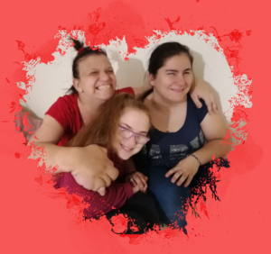 Zsófi, Eszti és Csilla ölelik egymást. Szélesen mosolyognak. A kép körül piros, szívalakú keret.