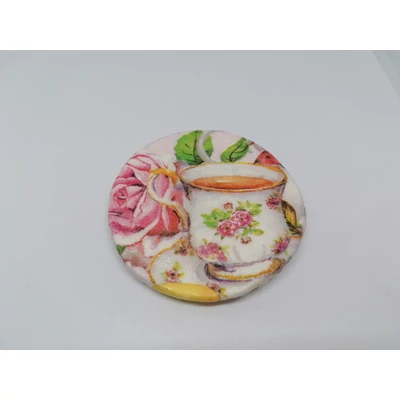 Köralakú hűtőmágnes, rózsás porcelán teáscsészével, a háttérben egy rózsaszín rózsával.