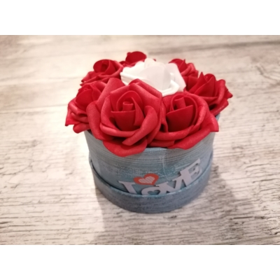 Kör alakú rózsabox oldalán love felirat olvasható, középen egy darab fehér rózsa van körülötte pedig piros rózsák vannak.