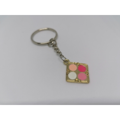 Ezüstszínű kulcskarikára rögzített láncról lelógó szemfesték aranyszínű paletta medál rózsaszínes árnyalatokkal.