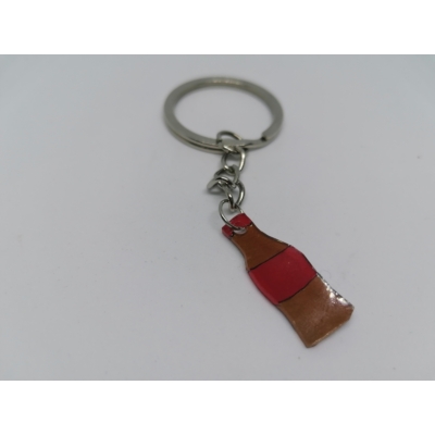 Ezüstszínű kulcskarikáról lánc lóg le, rajta a kulcstartó: barna üveges kóla piros címkével és kupakkal.