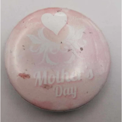 Köralakú kitűző: halványrózsaszín alapon fehér szív és kacskaringós minta, alatta felirat: Mother's Day.