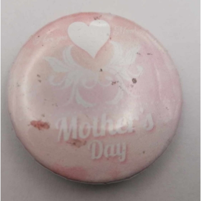 Köralakú kitűző: halványrózsaszín alapon fehér szív és kacskaringós minta, alatta felirat: Mother's Day.