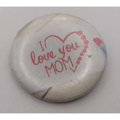 Köralakú kitűző: fehér lapra piros ceruzával I love you MOM feliratot írtak, körülötte szíves-csillagos keret.