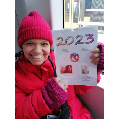 Zsófi a naptár előlapjával. A naptár A/4-es, felül fehér spirál. A borítón is rövid versrészlet, az alkotók bemutatkozása, illetve a 2023 szám festményes számokkal.