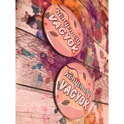 Rózsaszín alapon sárga színű könyv kinyitva könyvmoly vagyok szöveggel.  Köszönet : https://www.flaticon.com/authors/stickers 