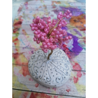 Fehér alapon öntött kő ezüst kacskaringós és pöttyös pufifesték mintákkal. Rajta drótból készült fa, aminek a leveleit apró, rózsaszín gyöngyök adják.