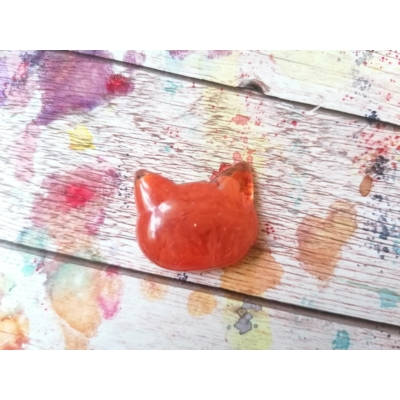 Narancssárga macskafej alakú apró mágnes. A körvonal, a fülek tapinthatók, konkrét arca nincs.