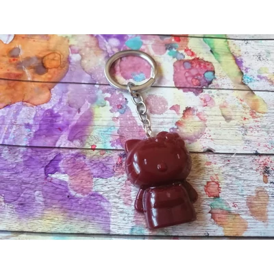 Ezüstszínű kulcskarikáról lelógó láncon kulcstartó: bordó hello kitty macska tapintható arccal, végtagokkal és fején lévő kis virággal. 