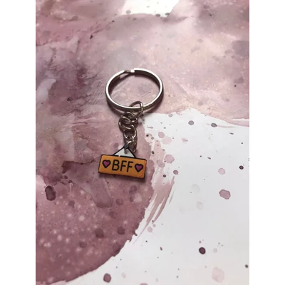 Ezüstszínű kulcskarikáról láncon lóg le egy bff feliratú minta