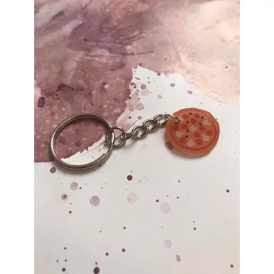 Ezüstszínű kulcskarikáról láncon lóg le egy egy egész pizza.