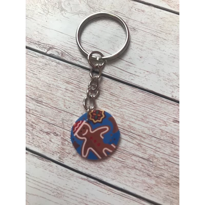 Ezüstszínű kulcskarikáról láncon lóg le egy nagyon aranyosan mosolygó mézeskalács emberke. 